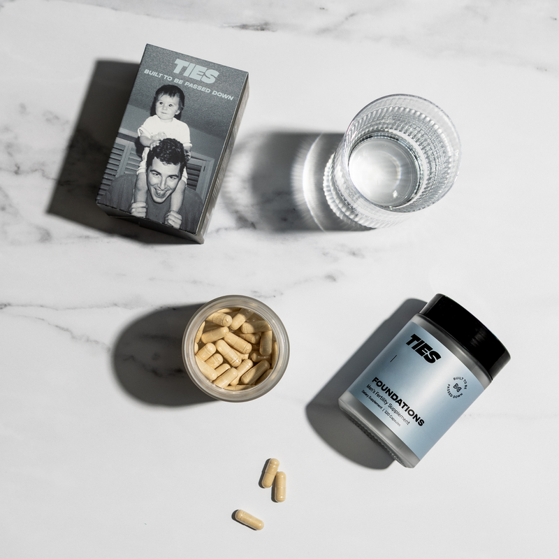 TIES Foundations men's fertility supplement capsules, jar, and packaging on marble